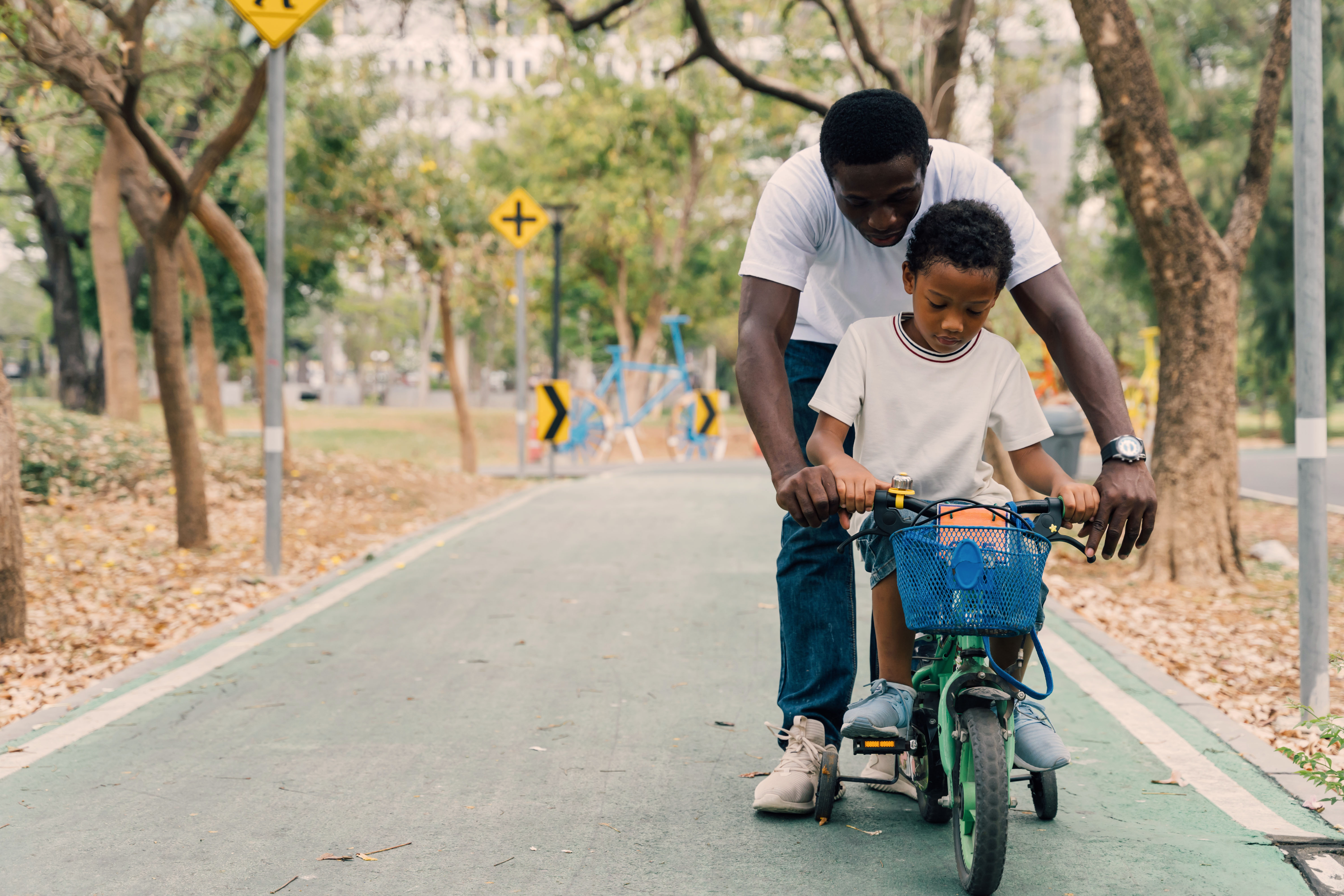A father helping his son ride his bike.